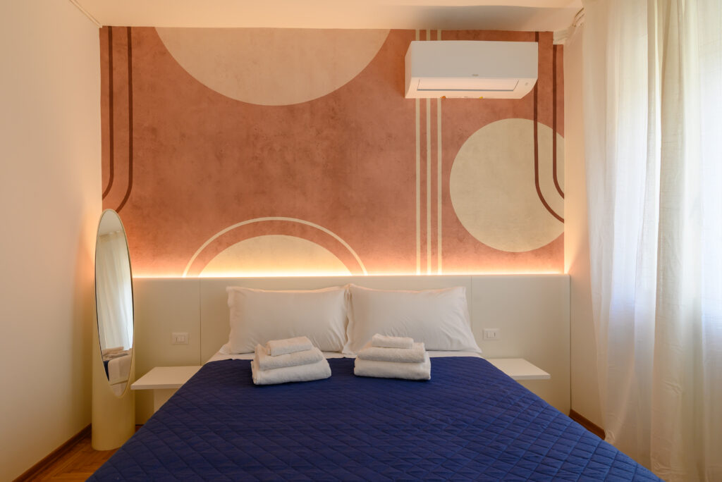 Vista frontale su letto matrimoniale e parete con murales, condizionatore.