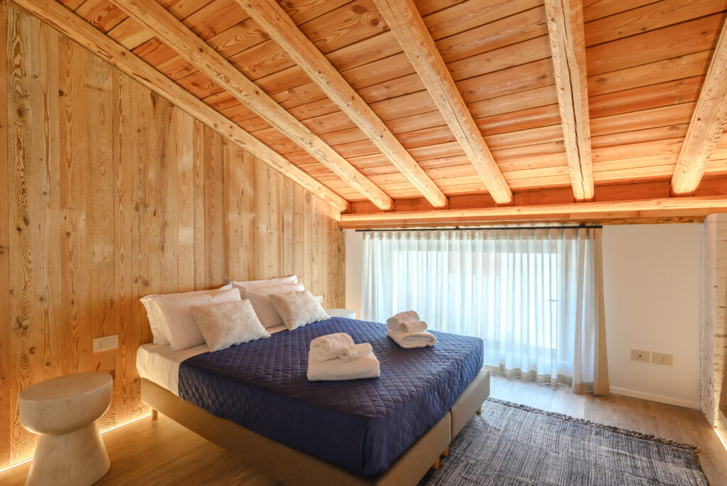 letto matrimoniale in ambiente rustico e moderno con soffitto a travatura