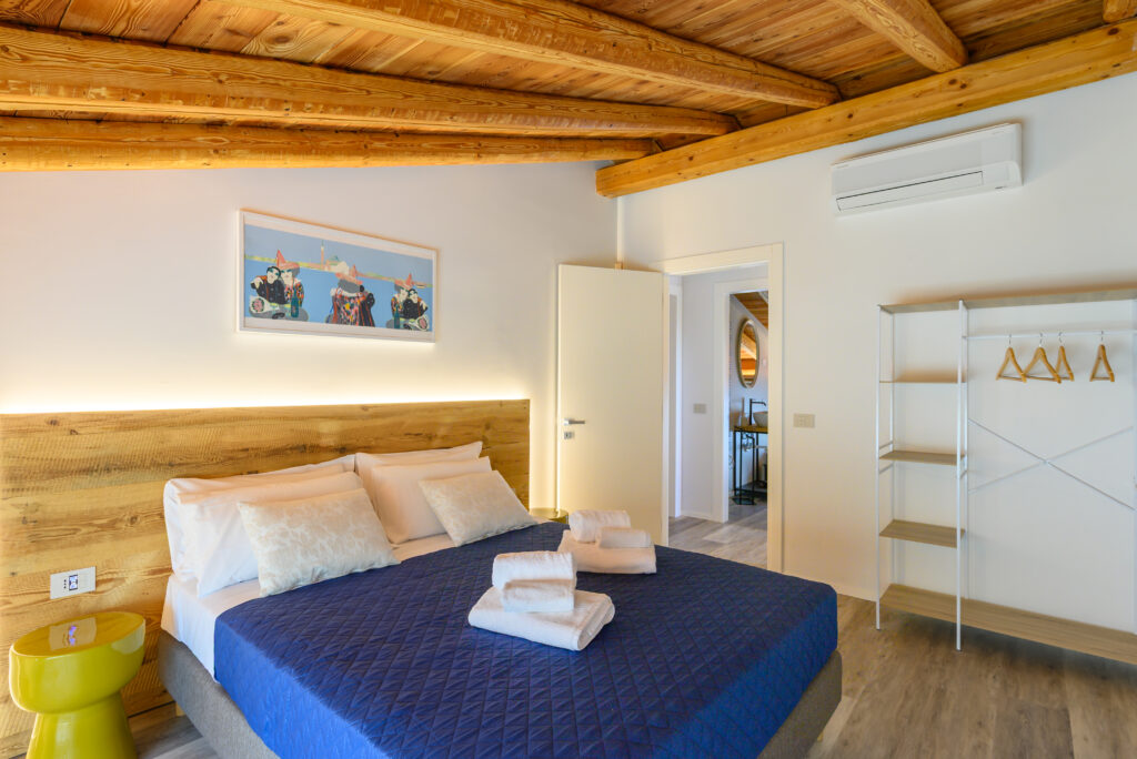 letto matrimoniale in ambiente rustico e moderno con soffitto a travatura