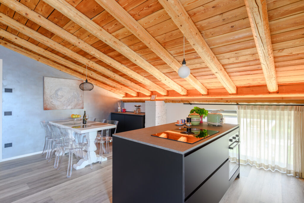 scorcio di cucina con tavolo e isola moderna colore antracite e soffitto a travatura luminosa