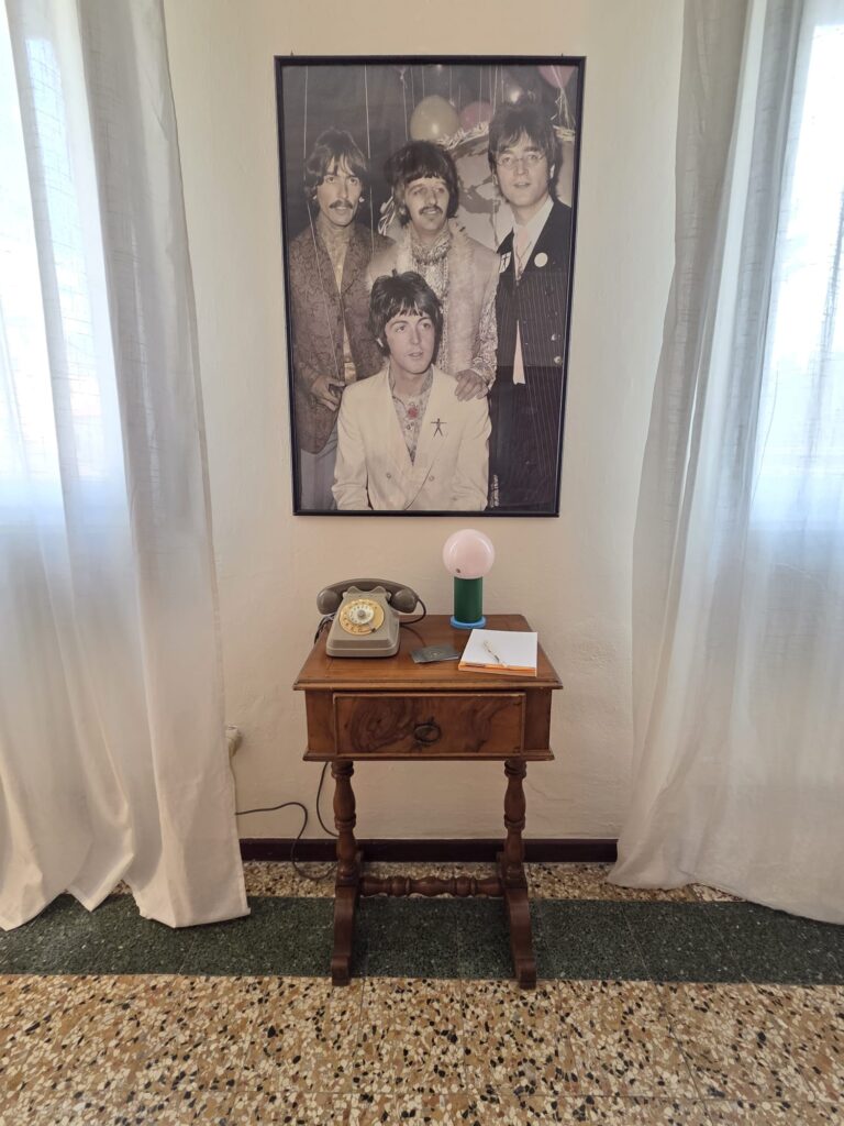 Angolo con tavolino antico e telefono retro, con sopra foto poster dei Beatles